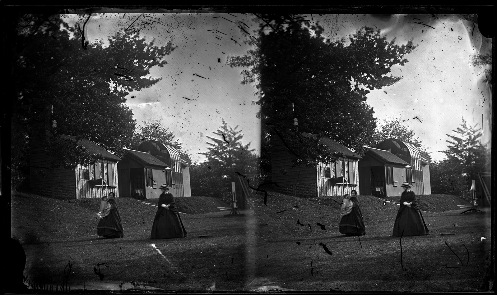 Stereoview of two women, one holding a baby [PHtempCB-A-16]. Unvarnished image shows extensive scratches. As the two women here are both slightly out of focus the photographer likely was not planning on using the image. Happily, the plate was not destroyed as the Rossie Priory darkroom and skylight studio can be seen clearly behind them.