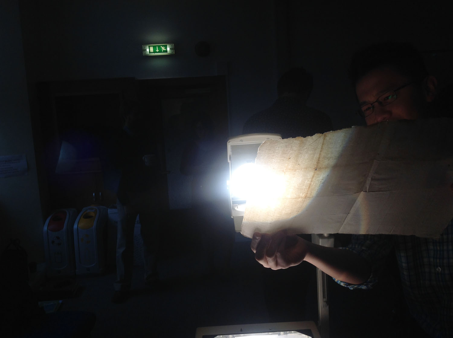 A student uses back-lighting from an old transparency projector to identify watermarks from a loose leaf of paper from Harris's own collection 