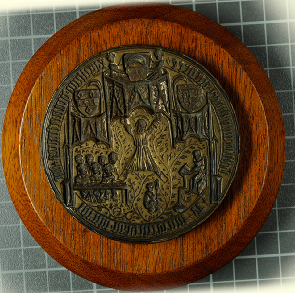 University seal matrix (1414x18), whose imagery includes heraldic insignia of the founders, and perhaps a rectorial court with bedellus holding the mace.